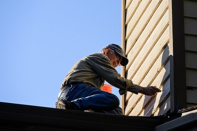 An older homeowner looking at a house in need of upkeep